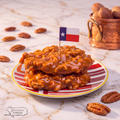 Two pecan pralines on a striped plate with a small Texas flag