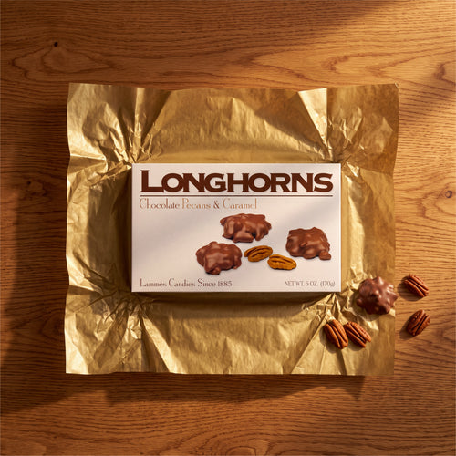 A box of Lammes Longhorns on gold foil with loose pecans